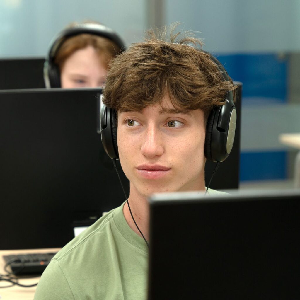 Una persone giovane che porta le cuffie di fronte un computer